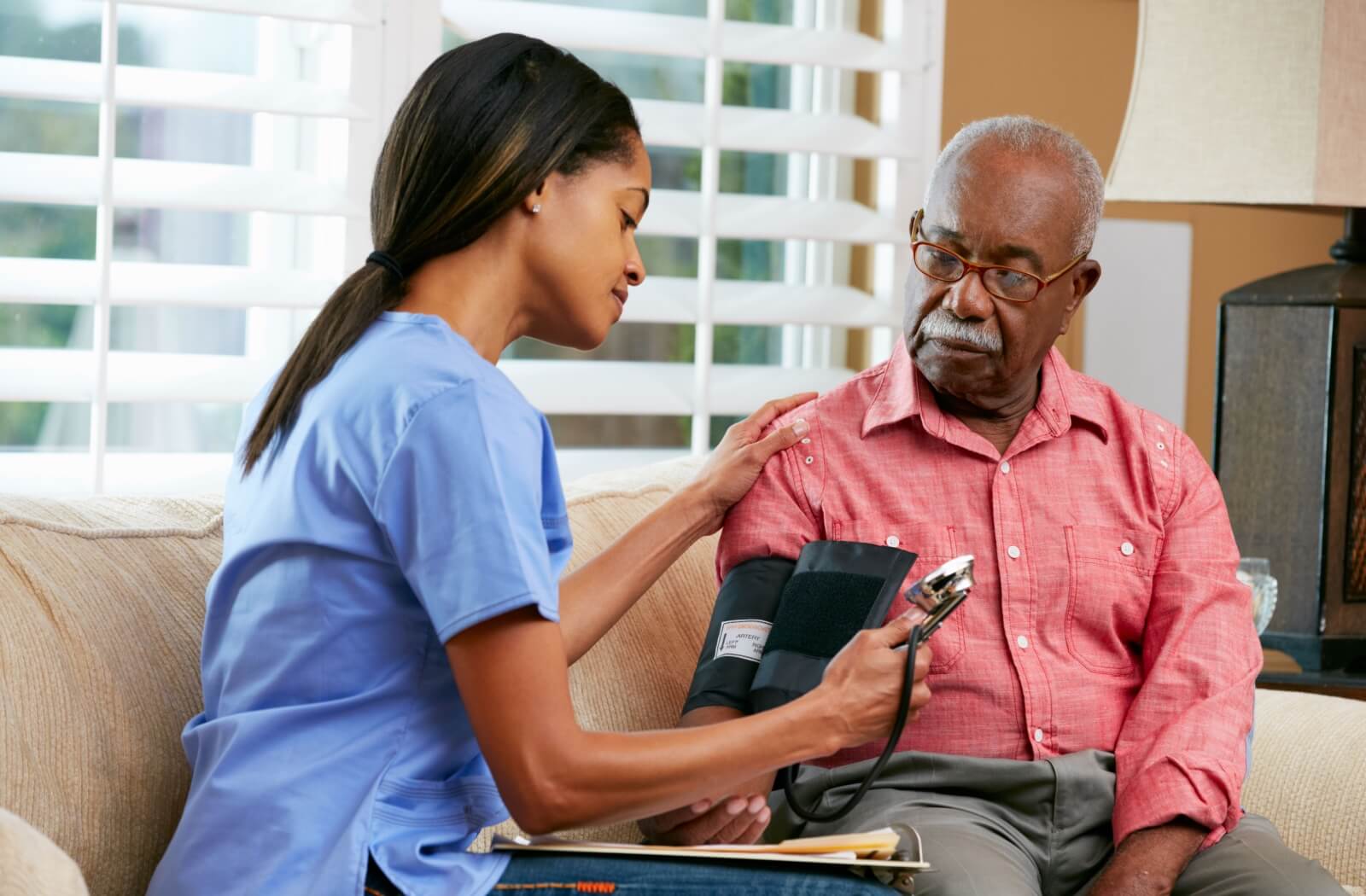 A nursing home staff checking the blood pressure of an older adult resident.