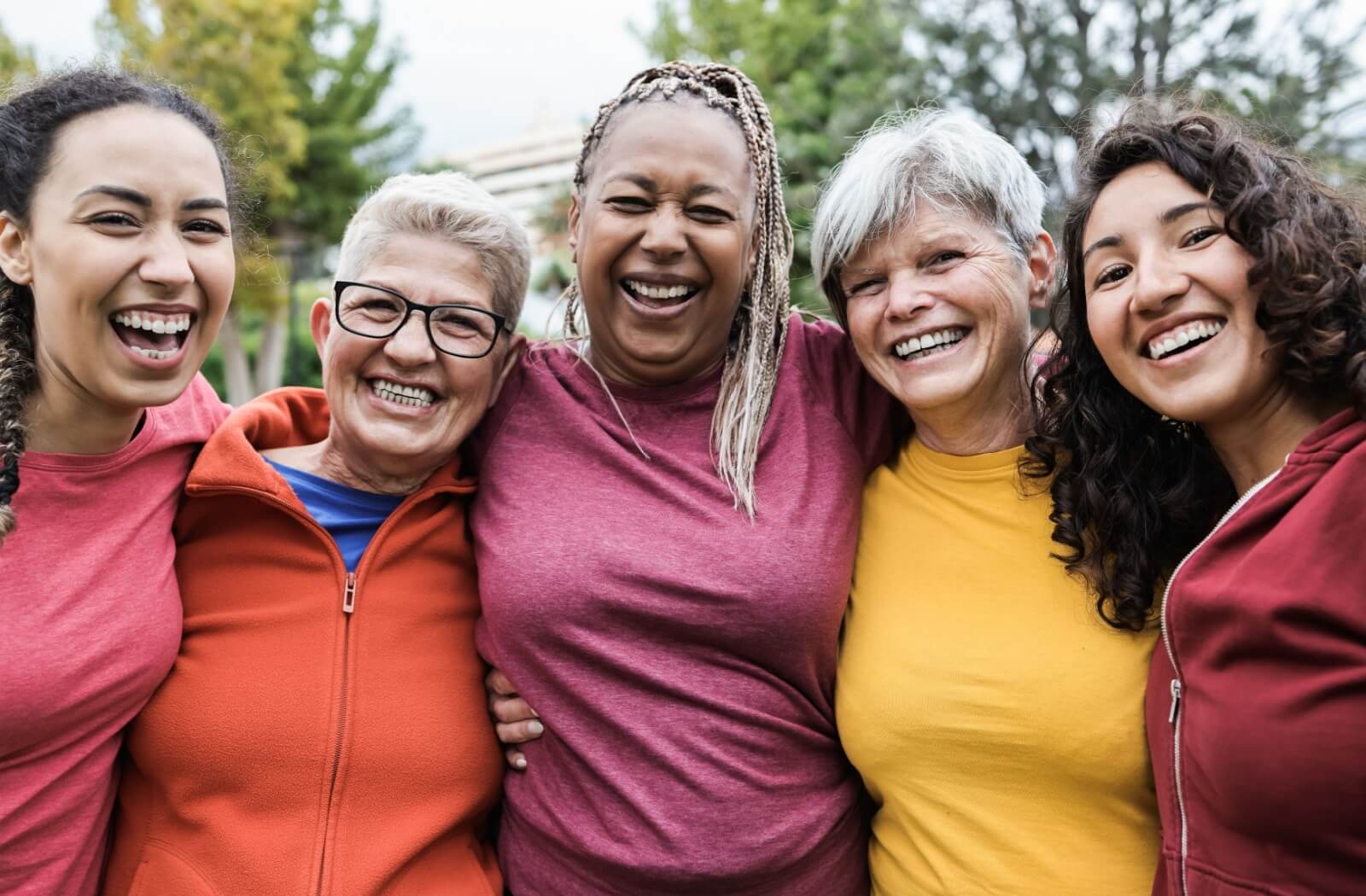 A diverse group of older adults embrace and pose for the camera.