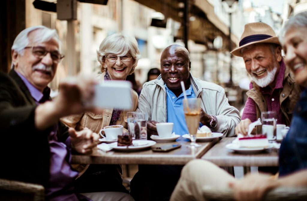 A diverse group of older adults take a picture together at a cafe.
