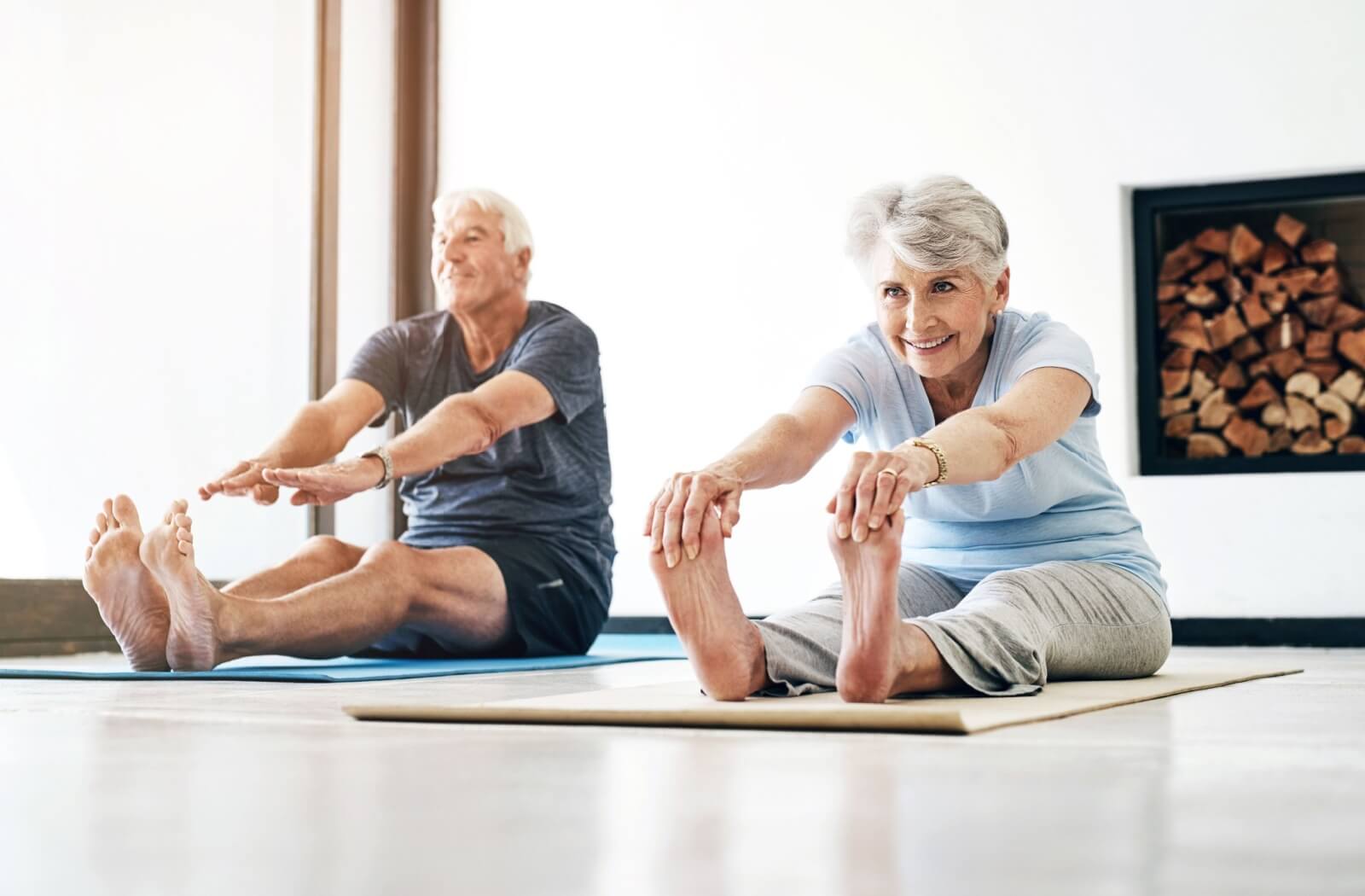 An older adult couple stretching on yoga mats in a yoga class in their senior living community.
