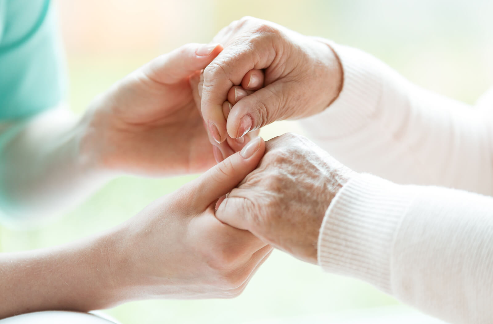 The hands of a compassionate nurse gently hold the hands of an elderly woman, providing comfort.